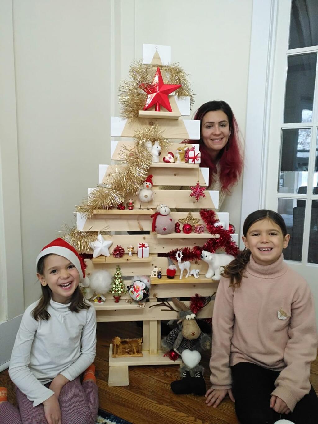 Joanna Guillaume com as filhas Anne (e) e Louise (d) e a árvore de Natal de madeira construída em casa.