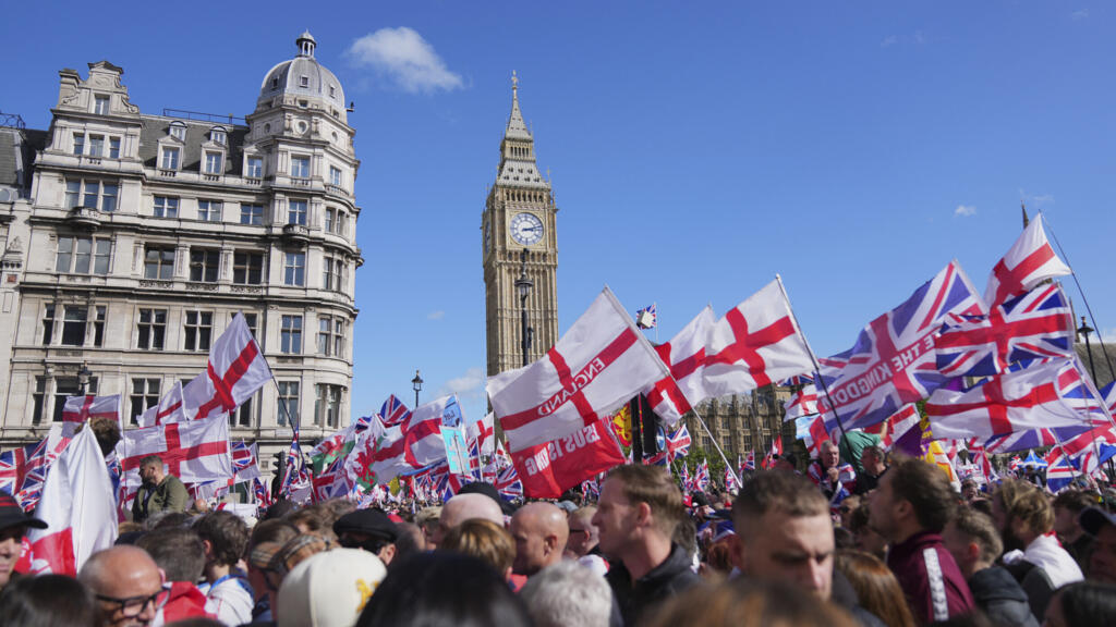 Des manifestants brandissent le drapeau de saint Georges lors de la marche et du rassemblement « Unite the Kingdom » organisés par Tommy Robinson à Londres, le samedi 13 septembre 2025.