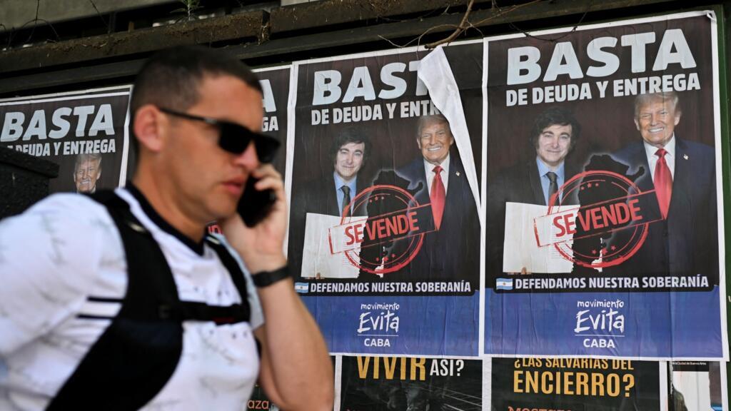 Homem passa diante de um cartaz com os presidentes Javier Milei e Donald Trump, em Buenos Aires, em 14 de outubro de 2025.