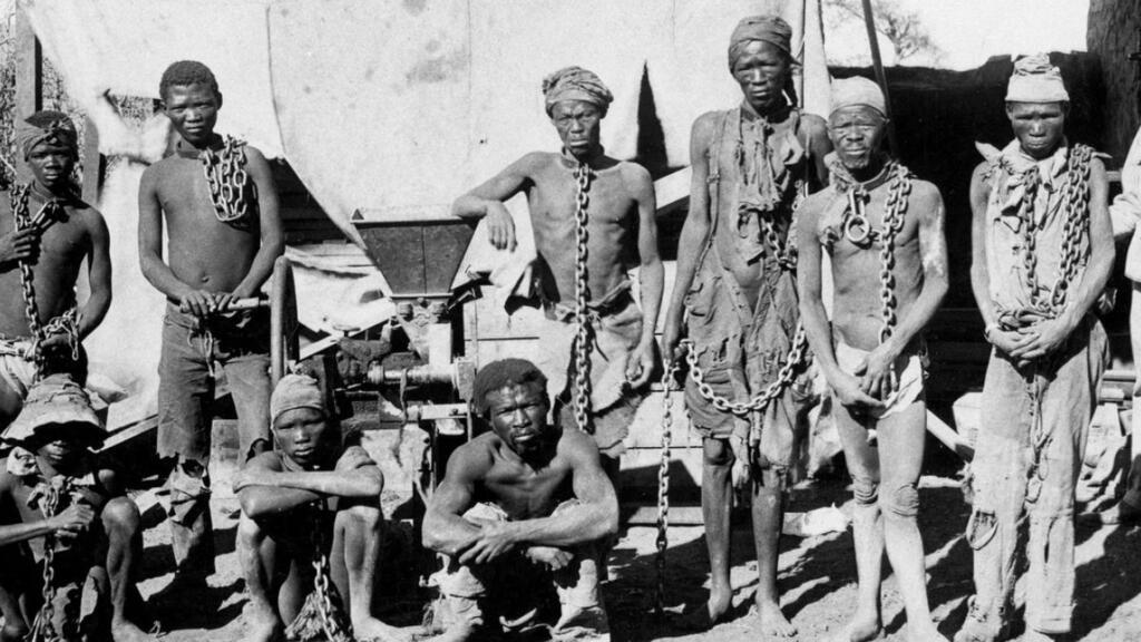 Un soldat appartenant probablement aux troupes allemandes surveillant des prisonniers de guerre namibiens sur une photographie prise pendant la guerre de 1904-1908 de l'Allemagne contre les Herero et les Nama. Archivos Nacionales de Namibia/AFP/Archivos