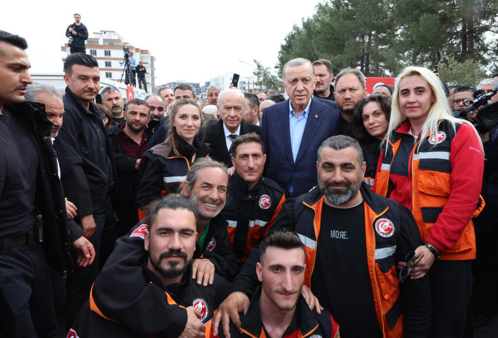 This handout photograph taken and released by the Turkish Presidental press service on February 27, 2023 shows Turkish President Recep Tayyip Erdogan (C-R) and the head of the nationalist MHP party Devlet Bahceli (C-L) posing for a photograph with rescue team members at Turkey's Disaster and Emergency Management Presidency (AFAD) coordination centre in Adiyaman following the February 6 earthquake.