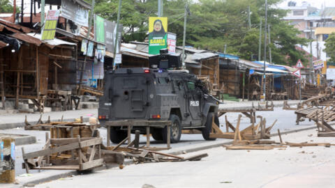 A Tanzanian police vehicle drives along a road barricaded by demonstrators during violent protests that marred the election following the disqualification of the two leading opposition candidates in Dar es Salaam, Tanzania, 29 October 2025. 