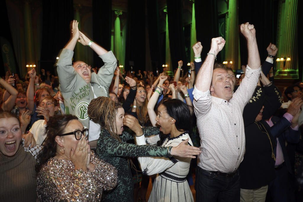 A secretária do Partido Ecologista “Os Verdes”, Katrin Wissing, em baixo à esquerda, de óculos, a porta-voz Amanda Lind, ao centro à esquerda, e os principais candidatos Alice Bah Kuhnke, ao centro à direita, e Pär Holmgren, à direita, celebram com outros membros do Partido Ecologista “Os Verdes” os resultados da sondagem das mesas de voto na vigília do Partido Ecologista “Os Verdes” em Nalen, Estocolmo, no domingo, 9 de junho de 2024.
