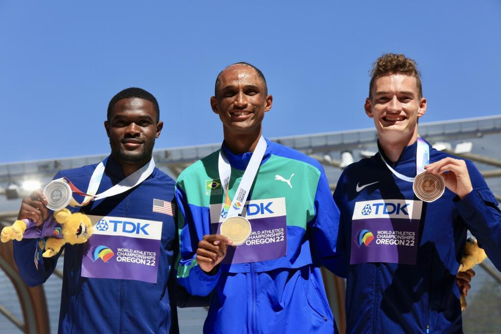 Imagem do pódio no estádio Hayward Field, na cidade de Eugene. Alison Santos, ouro, acompanhado dos norte-americanos Rai Benjamin (e) e Trevor Bassitt (d), medalhas de prata e bronze, respectivamente.