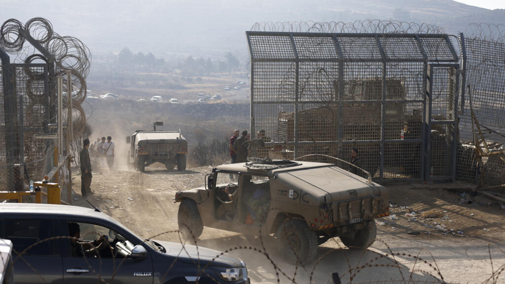 Des soldats israéliens montent la garde tandis que des membres de la communauté druze syrienne se dirigent vers la barrière pour passer dans le plateau du Golan annexé par Israël, près de Majdal Shams, le 17 juillet 2025.