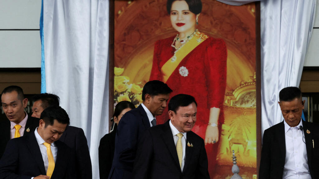 Former Thai Prime Minister Thaksin Shinawatra walks past an image of Thai Queen Sirikit, as he leaves after a Thai criminal court cleared him of charges in a lese majeste case, also known as a royal i
