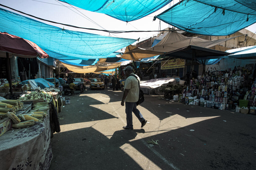 Un homme marche le long d'une allée du marché, couvert pour se protéger du soleil pendant les conditions de chaleur extrême, dans la ville de Basra, dans le sud de l'Irak, le 8 juillet 2023.