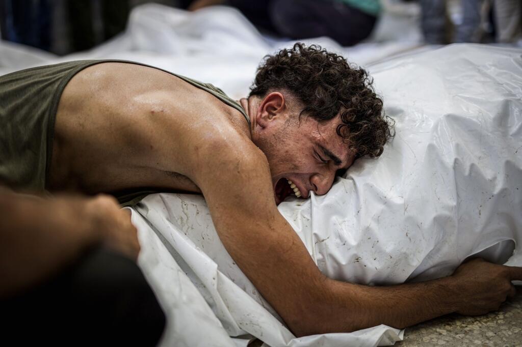 Un homme pleure en enlaçant le corps d’un proche enveloppé d’un linceul blanc à la morgue de l’hôpital des Martyrs d’Al-Aqsa à Deir al-Balah, à Gaza, le 13 août 2024. Plusieurs Palestiniens blessés et décédés sont arrivés à l’hôpital des Martyrs Al-Aqsa après des bombardements israéliens sur plusieurs zones du centre de la bande de Gaza.