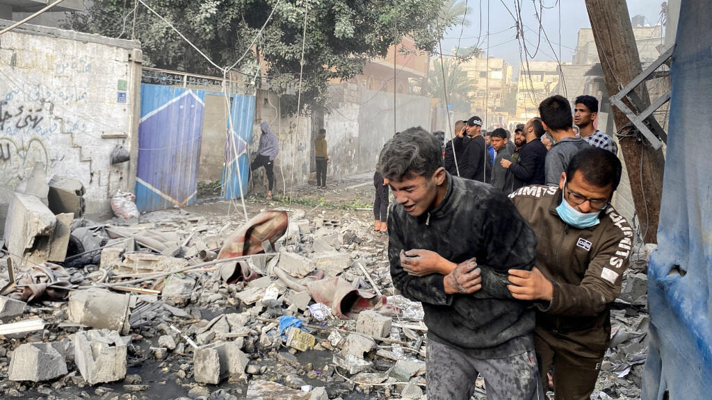 Un Palestinien assiste un garçon à la suite d'une frappe israélienne contre une maison, après l'expiration d'une trêve temporaire entre le Hamas et Israël, à Rafah, dans le sud de la bande de Gaza, le 1ᵉʳ décembre 2023.