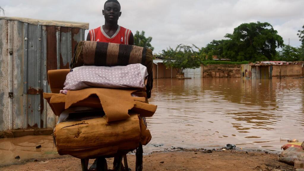 Un jeune homme transporte ses affaires après l'inondation de son village, près de Niamey, au Niger.