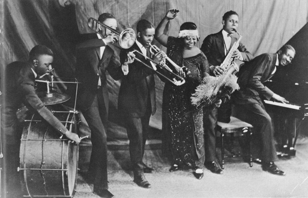 La «mère du blues» Ma Rainey et son groupe, les Rabbit Foot Minstrels, avec Ed Pollock, Albert Wynn, Thomas A. Dorsey (au piano à droite) Ma (Gertrude) Rainey, Dave Nelson et Gabriel Washington, posent pour un portrait vers 1924 à Chicago, Illinois.  