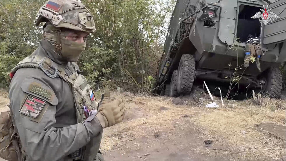 In this photo taken from video released by the Russian Defense Ministry on Friday, Sept. 13, 2024, a Russian soldier stands next to a damaged Ukrainian military vehicle in the Russian - Ukrainian bord