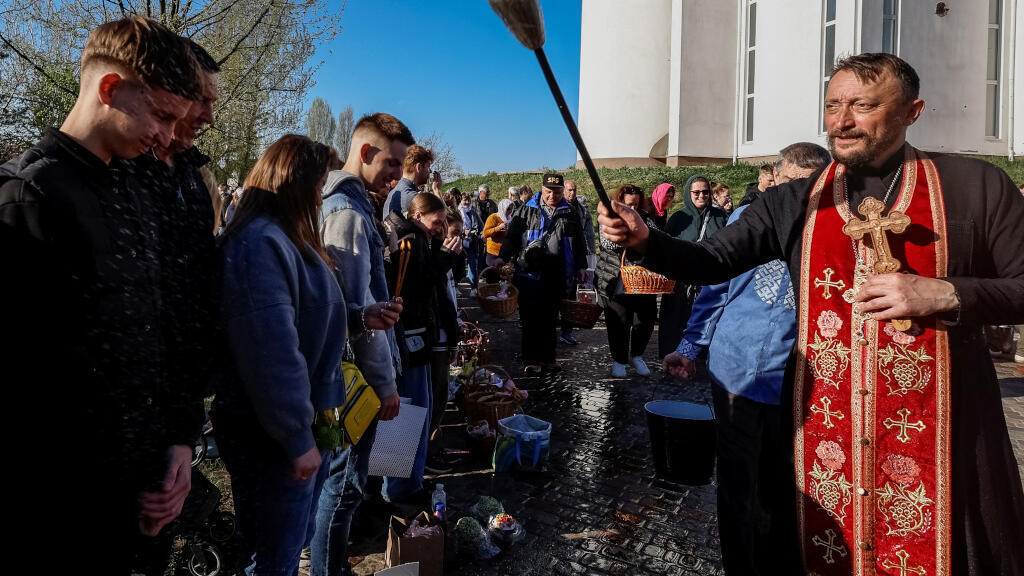 Des croyants ukrainiens assistent à une cérémonie de bénédiction des gâteaux de Pâques et des paniers de nourriture traditionnels après la messe, en pleine invasion russe contre l'Ukraine, devant l'église Saint-André dans la ville de Bucha, dans la région de Kiev, le 20 avril 2025.