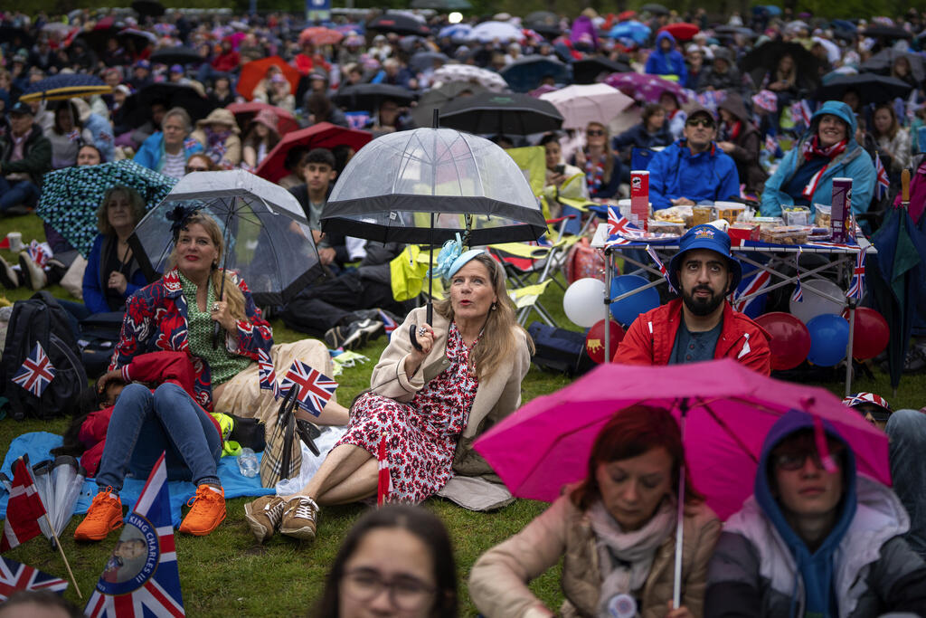 Admiradores da família real acompanham a cerimônia de coroação debaixo de chuva pelo telão instalado no Hyde Park, em Londres, neste sábado, 6 de maio de 2023.