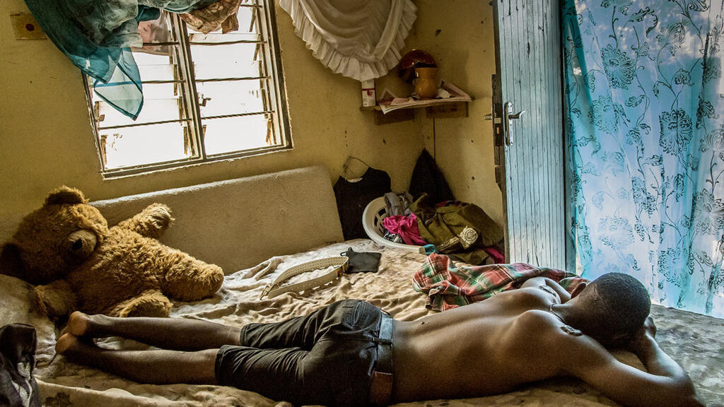 En plein après-midi, Simon sieste dans la maison d’un ami, dans un quartier excentré de Kampala. Il vient de Mbarara où il a échappé de peu à la mort. Sur ses épaules, des cicatrices, traces des coups reçus lors du lynchage par ses voisins.