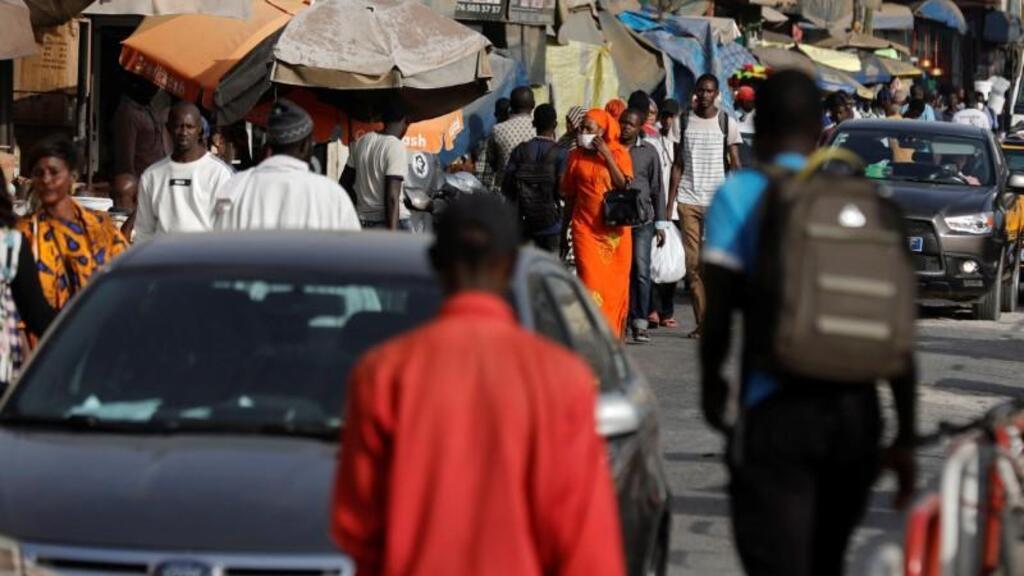 Une femme porte un masque en raison de l'épidémie mondiale de coronavirus alors qu'elle se promène dans une rue commerçante animée de Dakar, au Sénégal, le 18 mars 2020.
