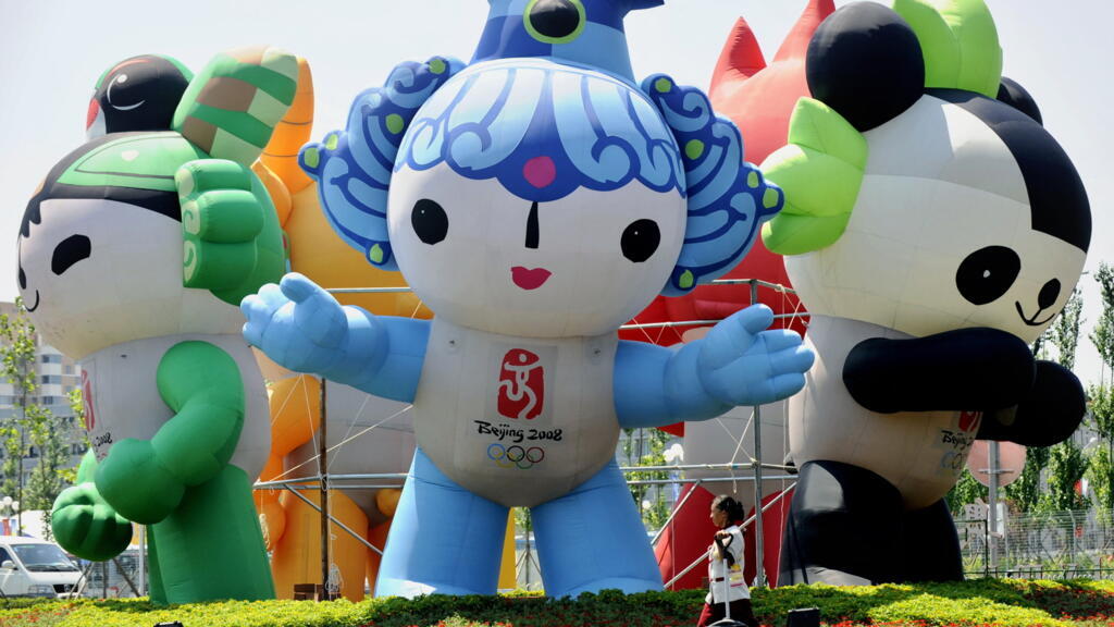 Un agent d'entretien passe devant une exposition des mascottes des Jeux olympiques de Pékin au village olympique abritant les athlètes, le 2 août 2008.