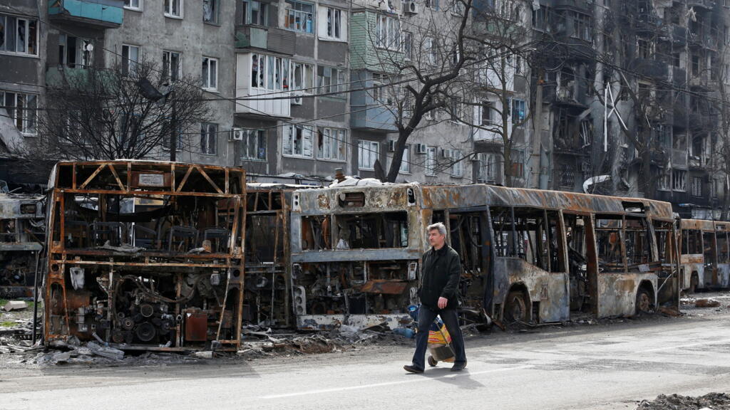 Un habitant de Marioupol (Ukraine) passe devant des bus brûlés, le 19 avril 2022.