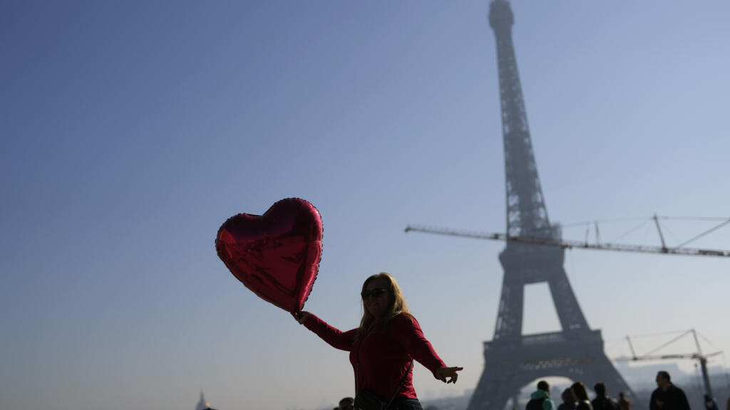 Une femme tient un ballon rouge en forme de cœur pendant la Saint-Valentin, devant la Tour Eiffel, à Paris, mardi 14 février 2023.