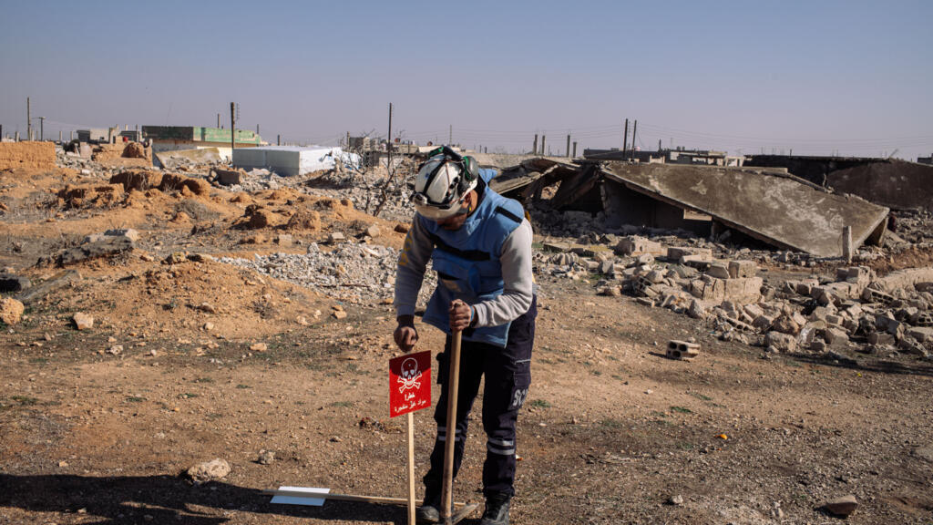 Un membre de l'équipe de déminage des casques blancs installe un panneau prévenant de la présence de mine dans un village a proximité de Homs, en Syrie, le 4 février 2025.