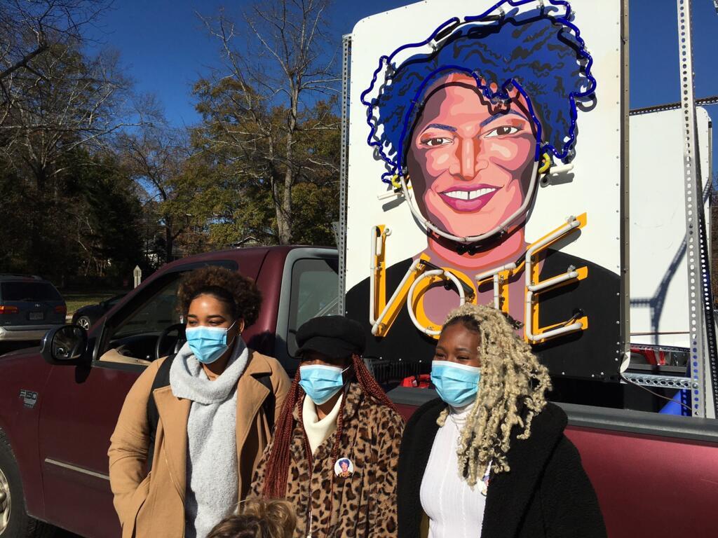 De jeunes afro américaines devant le portrait de Stacey Abrams.