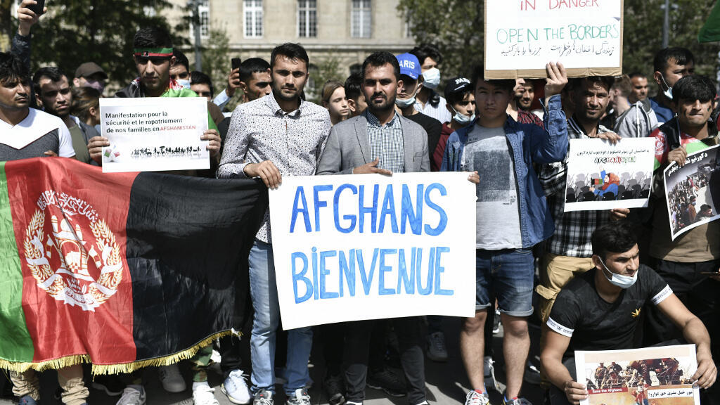 Des manifestants tiennent un drapeau national afghan et des banderoles lors d'un rassemblement de soutien à l'Afghanistan à la suite de la prise de contrôle du pays par les talibans, à la Place de la République à Paris le 22 août 2021.