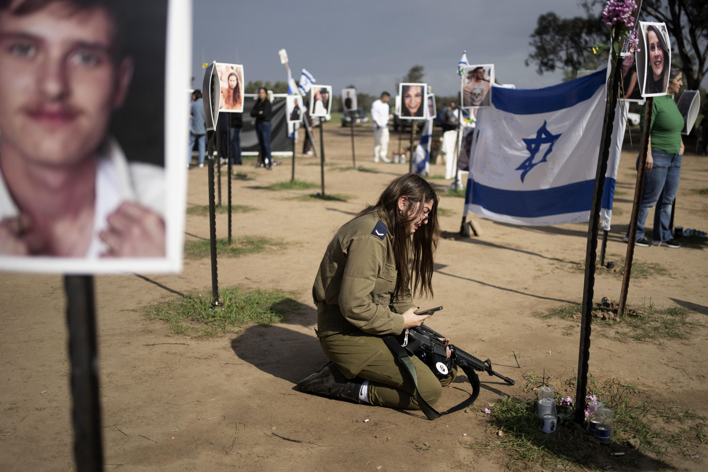 Soldado israelense chora em meio a fotos de vítimas dos ataques de 7 de outubro na rave Tribo Nova, em Re'im, no sul de Israel. (05/01/2024)