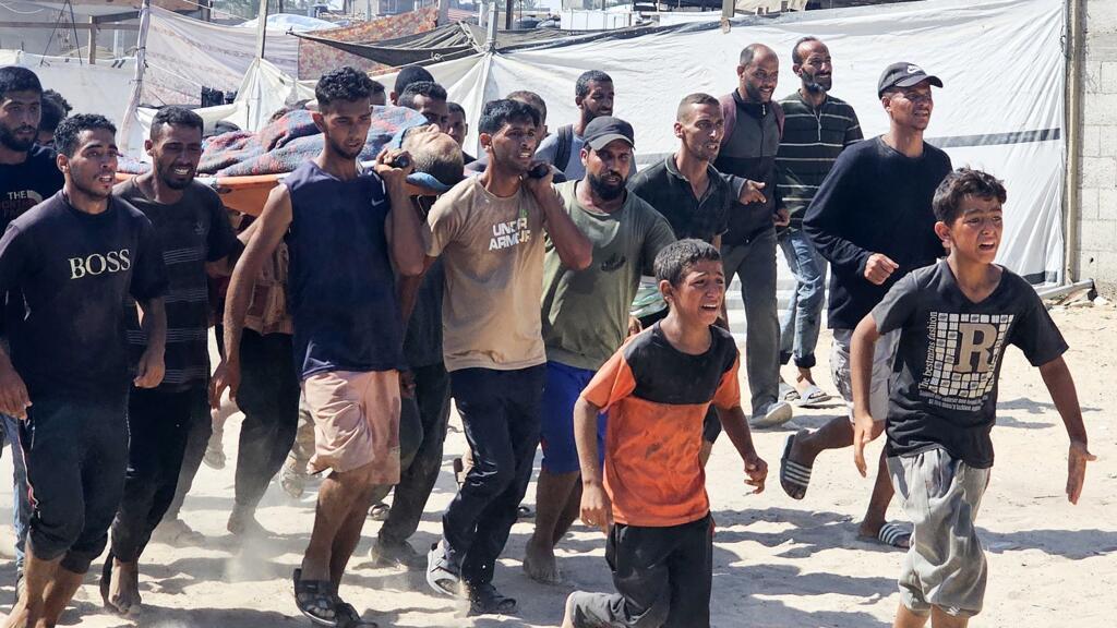Des Palestiniens transportent une victime vers une clinique de la Croix-Rouge à Rafah, dans le sud de la bande de Gaza, après avoir été abattu alors qu'il attendait de recevoir des colis alimentaires à un point de distribution géré par la Fondation humanitaire de Gaza (GHF), soutenue par les États-Unis et Israël, le 12 juillet 2025.