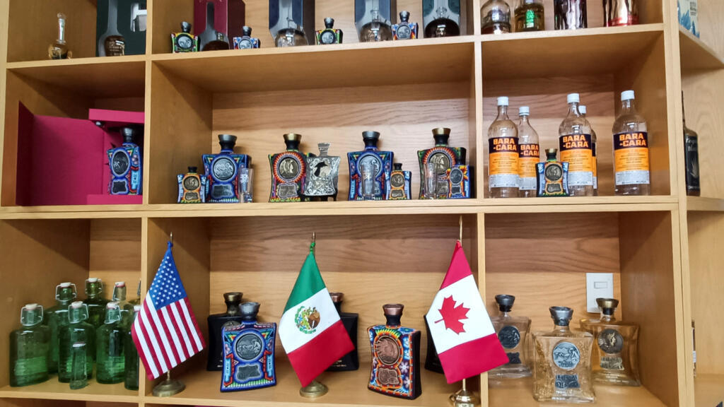 As bandeiras dos Estados Unidos, México e Canadá são exibidas em uma prateleira da Aguila Azteca Wines and Spirits, destilaria no Vale de Guadalupe, Jalisco, México, 10 de fevereiro de 2025. 