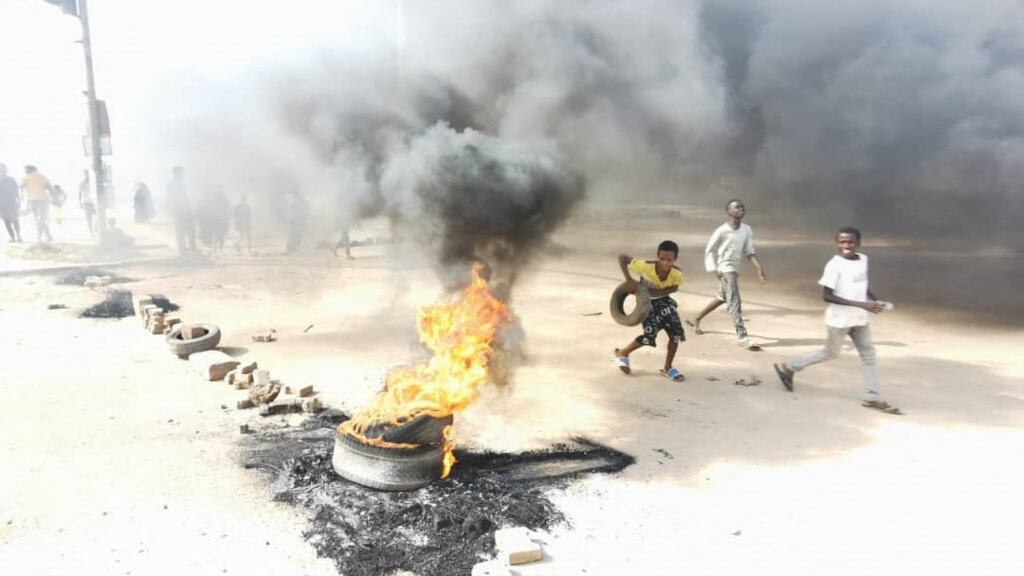 De jeunes enfants devant une barricade faite de pneus enflammés, à Khartoum, le 25 octobre 2021.