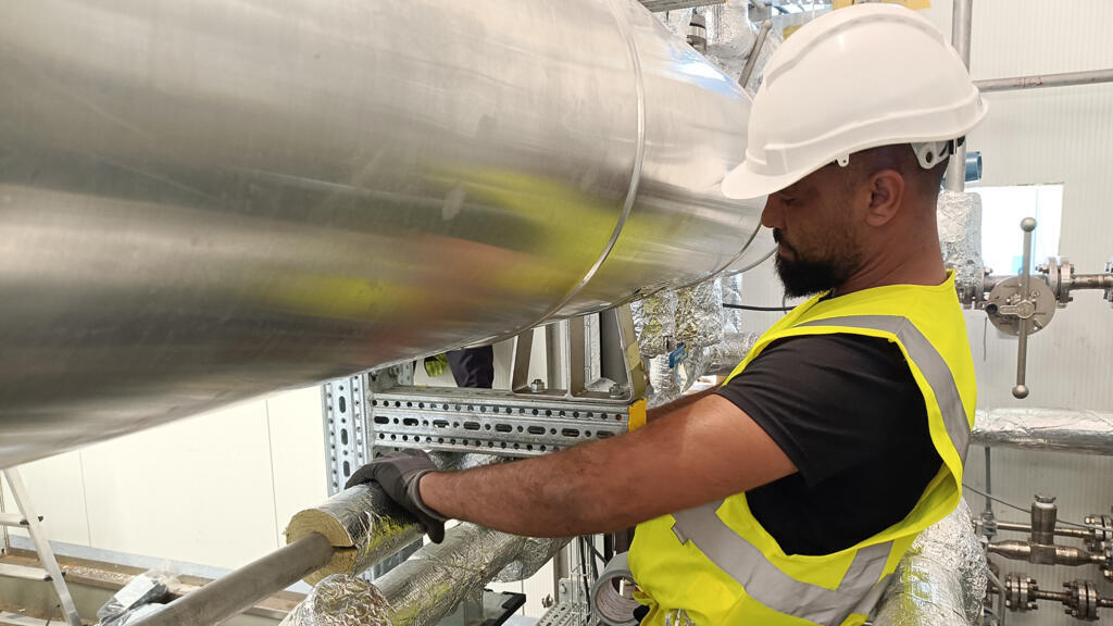Un salarié de Vulcan installe de l'isolant sur des tuyaux par lesquels passeront des saumures de géothermie, desquelles l'entreprise prévoit d'extraire du lithium, à Landau (Allemagne).