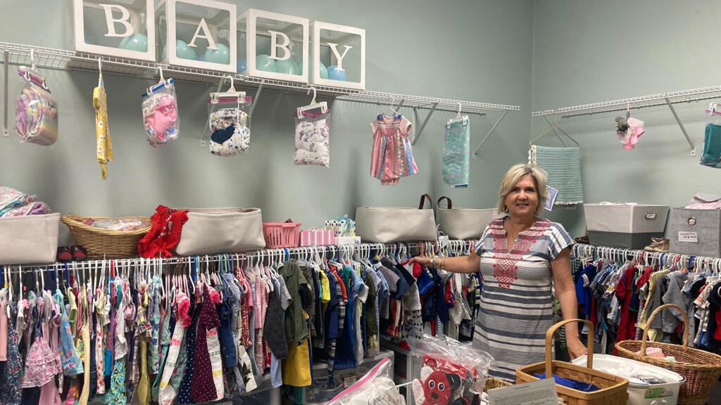 Susan Kremer Jones, directrice du Centre de Ressources pour les femmes de Gulfport, pose dans la boutique de vêtements pour enfants. Les femmes y ont accès en échange de leur présence aux cours de parentalité dispensés par le centre.