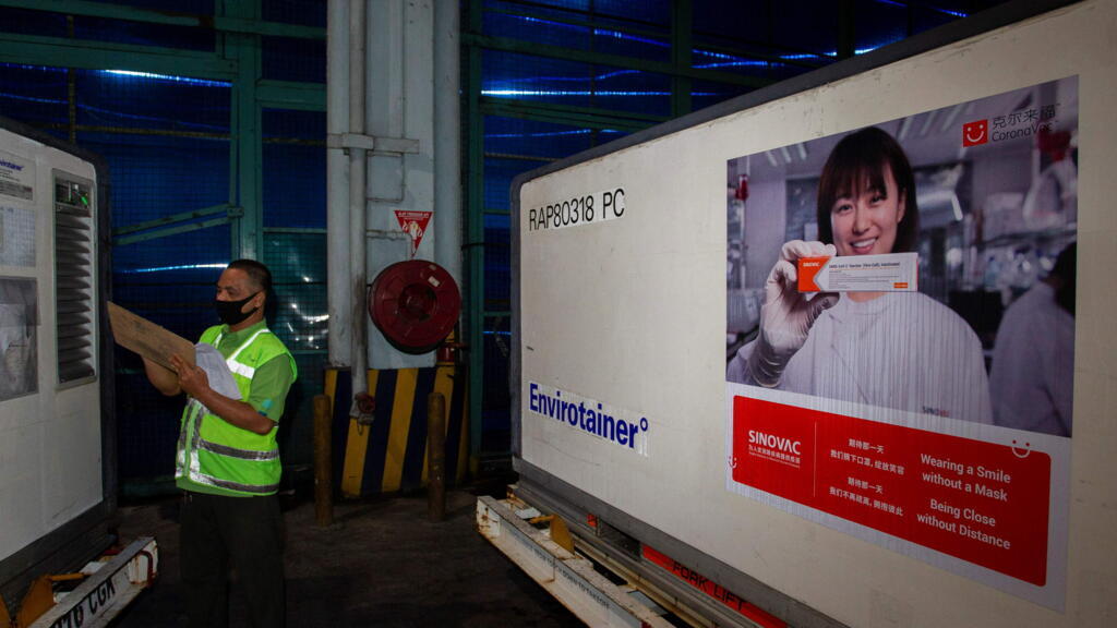 Un agent vérifie un conteneur contenant des vaccins Covid-19 de la société chinoise Sinovac Biotech Ltd., à leur arrivée à l'aéroport international de Soekarno-Hatta lors du premier envoi en Indonésie, à Tangerang, près de Jakarta, le 6 décembre 2020.