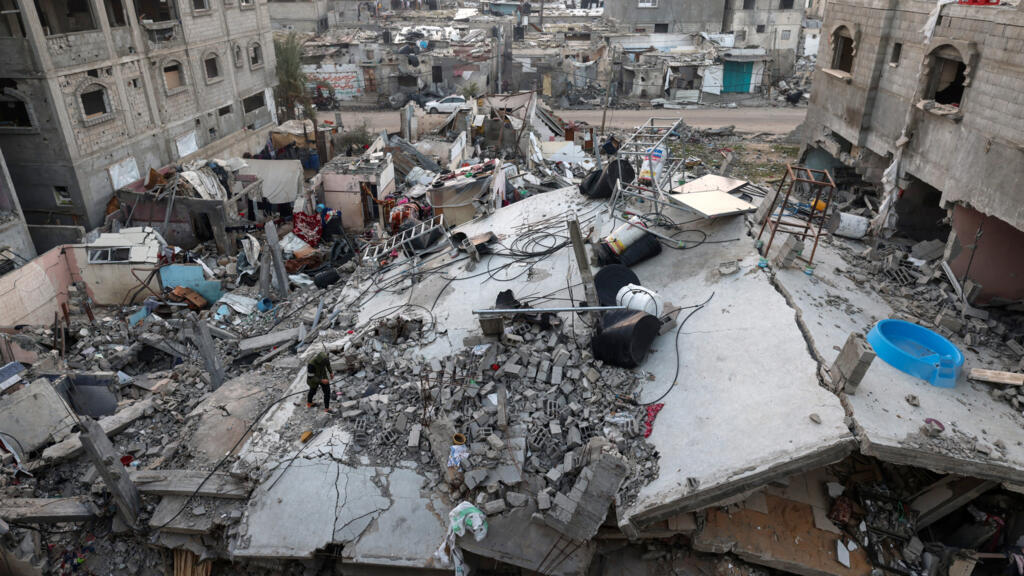 Cette photographie prise le 1ᵉʳ janvier 2024 montre un Palestinien marchant sur les décombres d'un bâtiment effondré à Rafah, dans le sud de la bande de Gaza, après un bombardement israélien.
