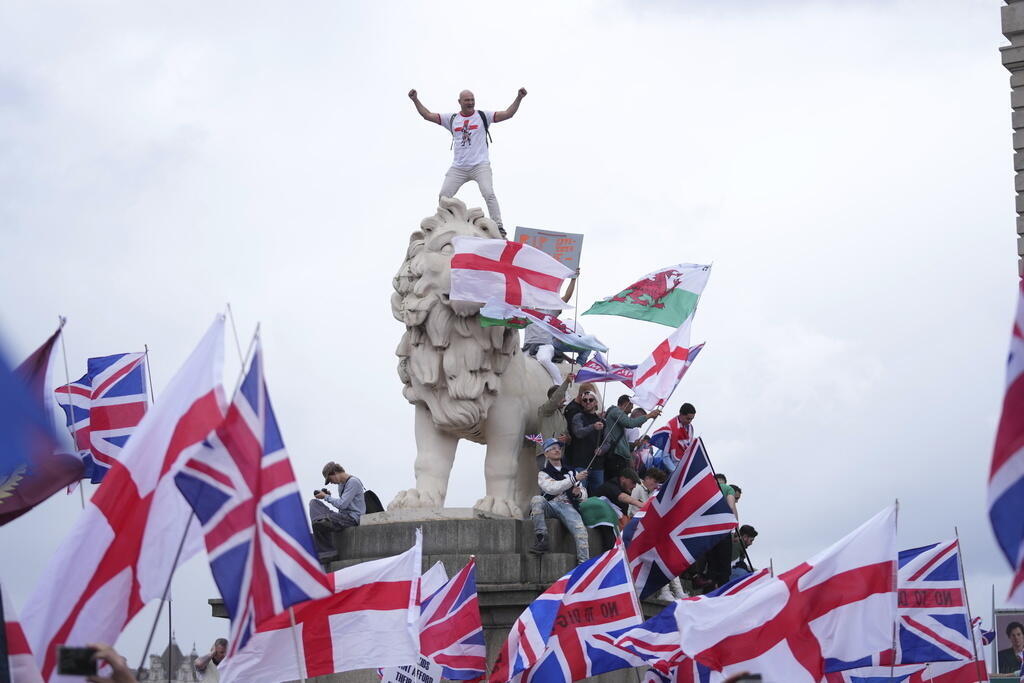 Um manifestante sobe na cabeça de um dos leões da Ponte de Westminster durante uma marcha liderada pelo ativista de extrema direita Tommy Robinson em Londres. Em 13 de setembro de 2025.