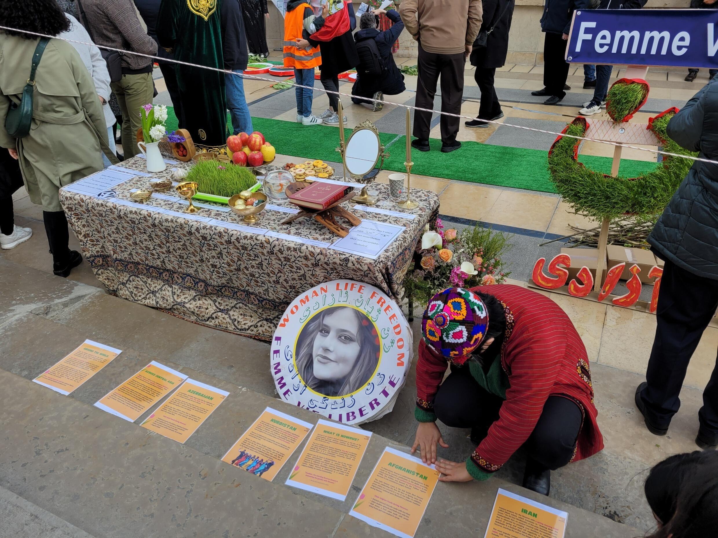 Des pancartes scotchées au sol expliquent la situation des droits des femmes dans plusieurs pays célébrant Norouz, sur le parvis des droits de l’homme à Paris, le 25 mars 2023.