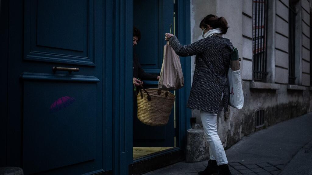 Un membre de l'association AMAP (Association pour le maintien d'une agriculture paysanne) rapporte un panier de légumes à une personne confinée dans son appartement à Paris, le 18 mars 2020.