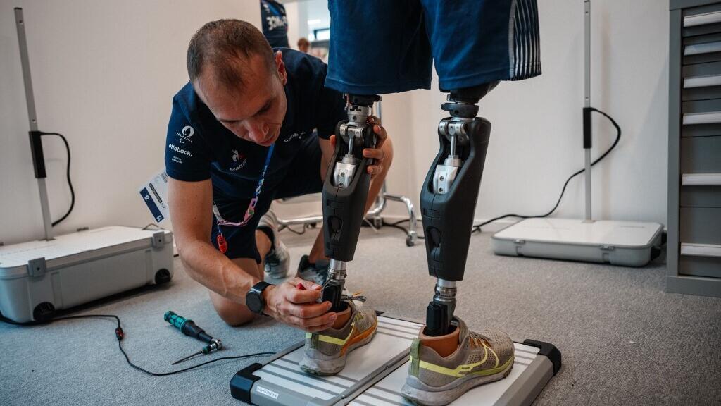 Un technicien ajuste les jambes prothétiques du para-athlète français Alexis Sanchez au centre de réparation prothétique Ottobock du village des athlètes paralympiques de Saint-Denis, le 24 août 2024, en prévision des Jeux paralympiques de Paris 2024.