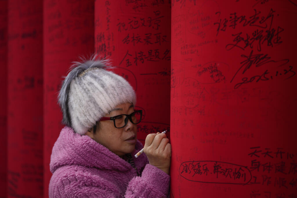 Pékin, le 29 janvier 2025, jour du Nouvel an : cette femme écrit ses voeux pour la Nouvelle année sur la colonne.