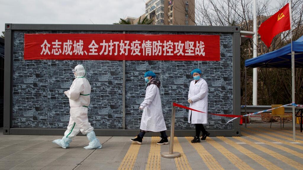 Le personnel de l'hôpital en vêtements de protection marche à un point de contrôle vers la zone d'exclusion de la province du Hubei au pont du fleuve Jiujiang Yangtze à Jiujiang, province du Jiangxi, en Chine, le 1er février 2020.