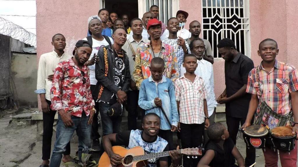 Jupiter Bokondji entouré par les jeunes musiciens qu’il aide à progresser, chez lui dans sa maison à Kinshasa.