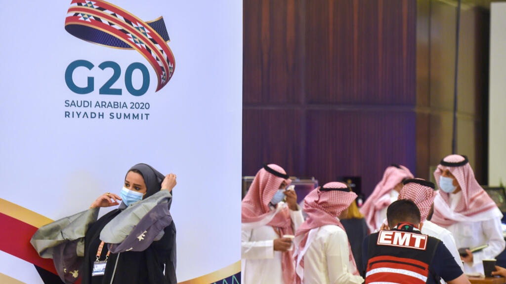 Una mujer pasa delante de un cartel de la cumbre del G20 nations en Riad, la capital saudita, el 18 de noviembre de 2020