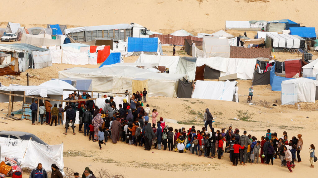 Palestinos fazem fila para aguardar o recebimento de ajuda humanitária em Rafah.