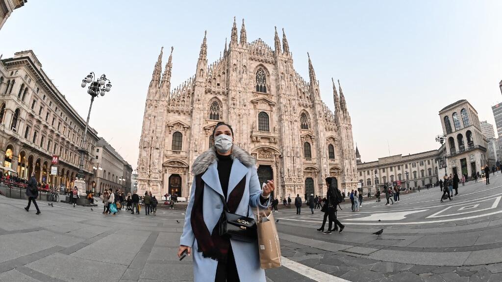 Une femme sur la Piazza del Duomo dans le centre de Milan porte un masque de protection contre l'épidémie du coronavirus, le 24 février 2020.