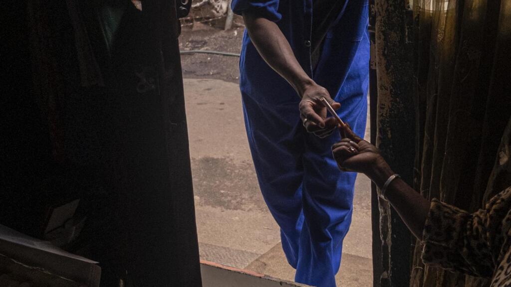Une femme vend une cigarette à un homme, le 9 avril 2020 alors que le gouvernement a interdit la vente de cigarettes et d'alcool pendant toute la période du confinement en Afrique du Sud.