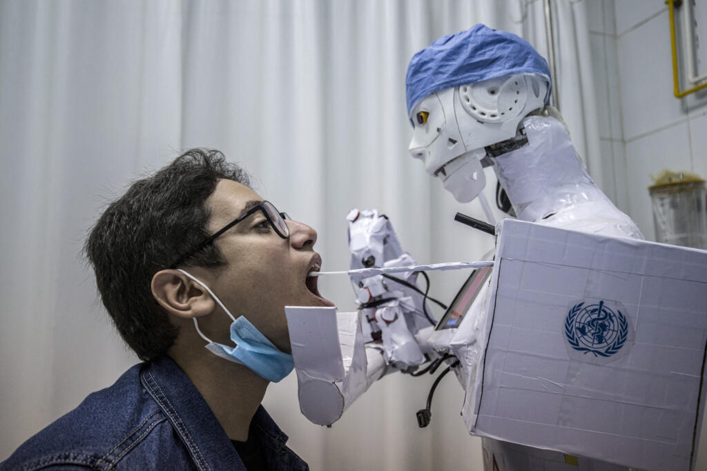 Protótipo do robô controlado remotamente CIRA-03 aproxima-se da boca de um voluntário para extrair uma amostra da garganta, como parte de um projeto autofinanciado para ajudar os médicos a realizar testes em pacientes suspeitos de COVID-19, numa tentativa de limitar a exposição humana a portadores da doença, num hospital privado na cidade de Tanta, no delta do Nilo, no Egito, em 20 de março de 2021.