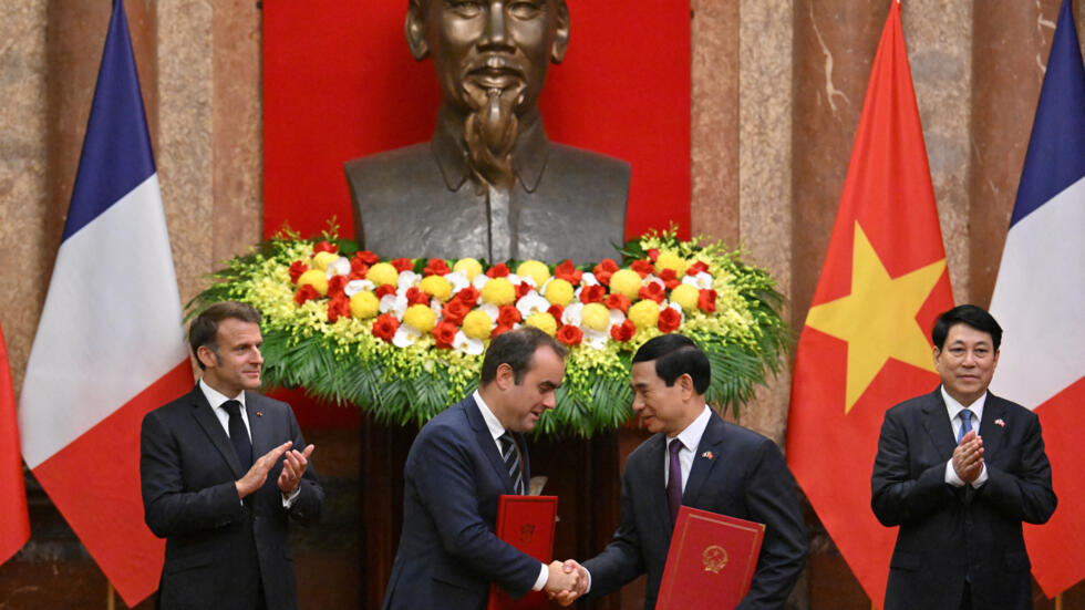 fFrance's President Emmanuel Macron and Vietnam's President Luong Cuong applaud as France's Minister of Armed Forces Sebastien Lecornu and Vietnam's Defense Minister Phan Van Giang exchange agreements