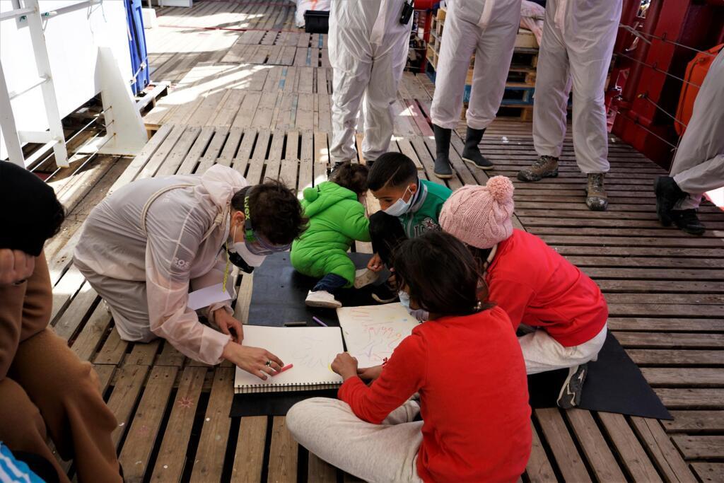 Leslie apporte des feuilles de papier et des crayons pastel. Les quatre enfants présents sur le bateau s’en emparent.