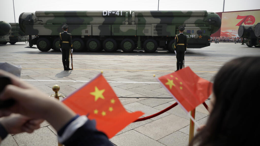 Spectators wave Chinese flags as military vehicles carrying DF-41 nuclear ballistic missiles roll during a parade to commemorate the 70th anniversary of the founding of Communist China in Beijing on O