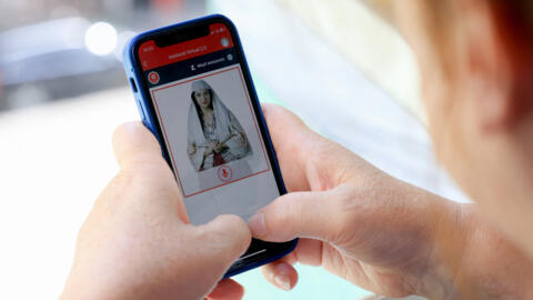 A woman looks at a phone as she uses the Albanian government portal "E - Albania", now assisted by government artificial intelligence cabinet minister avatar "Diella".